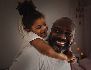 Daughter hugging smiling dad's neck